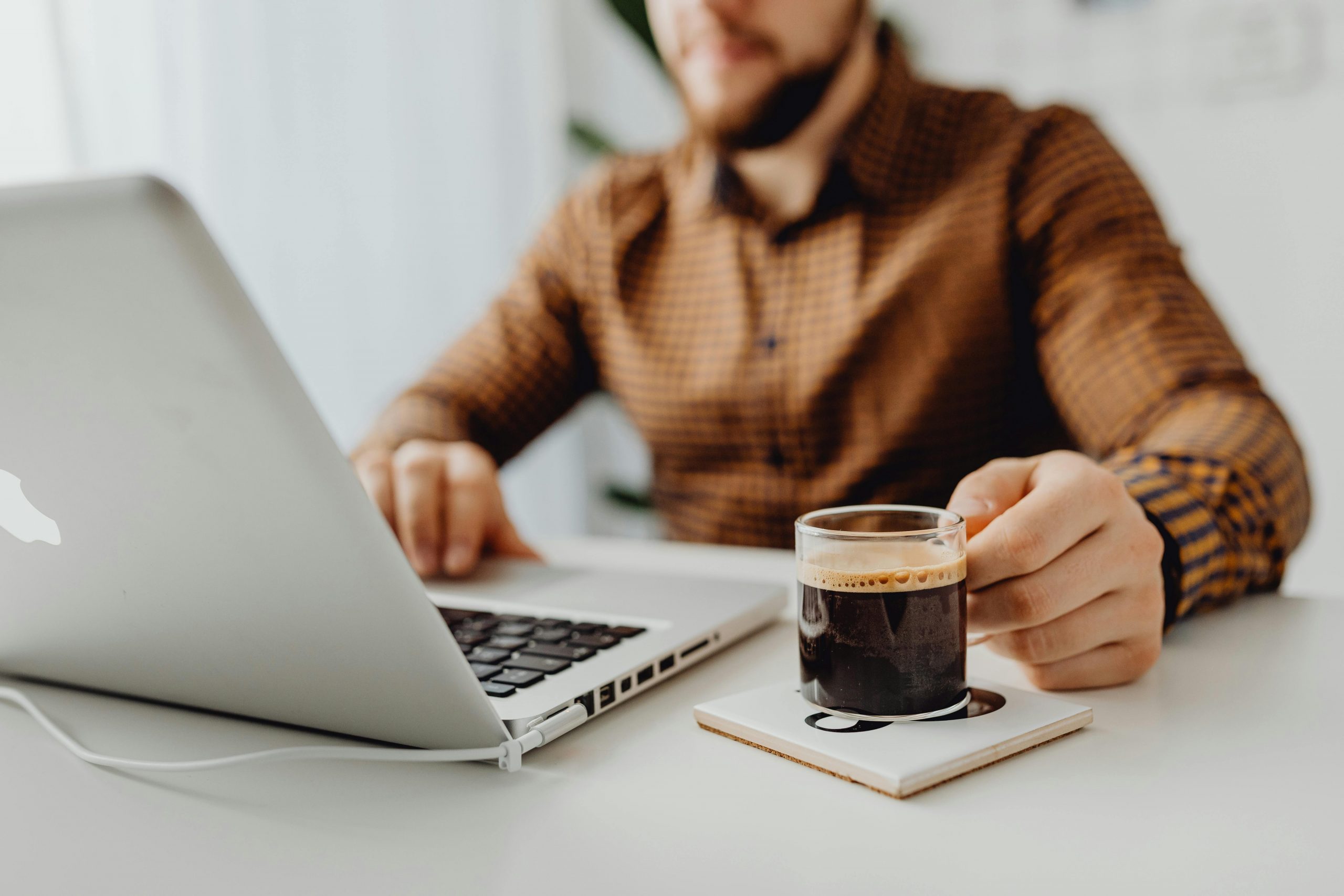 man using a touchpad with one hand and holding a cup of coffee with another
